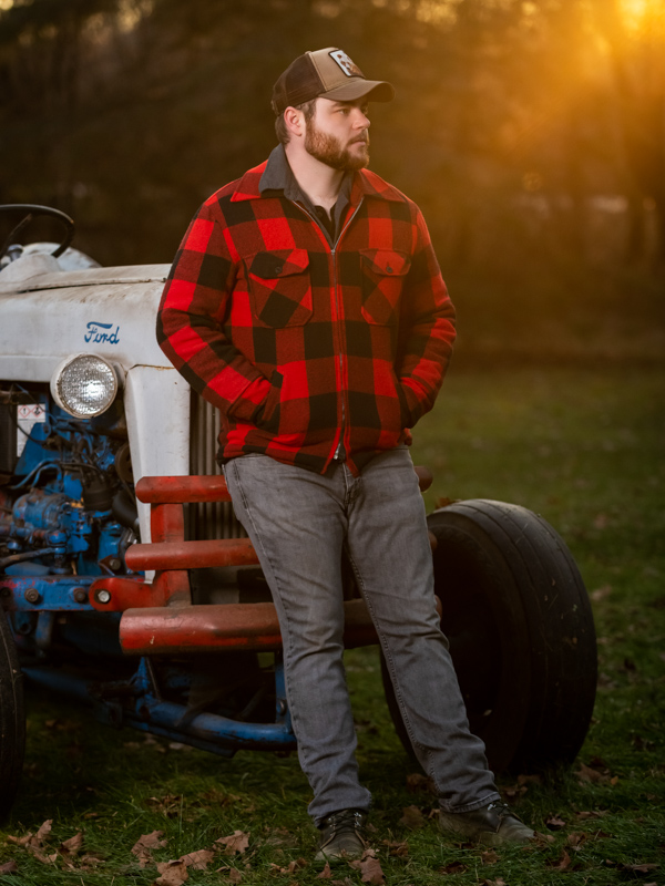 Color; Young man leaning against an old tractor